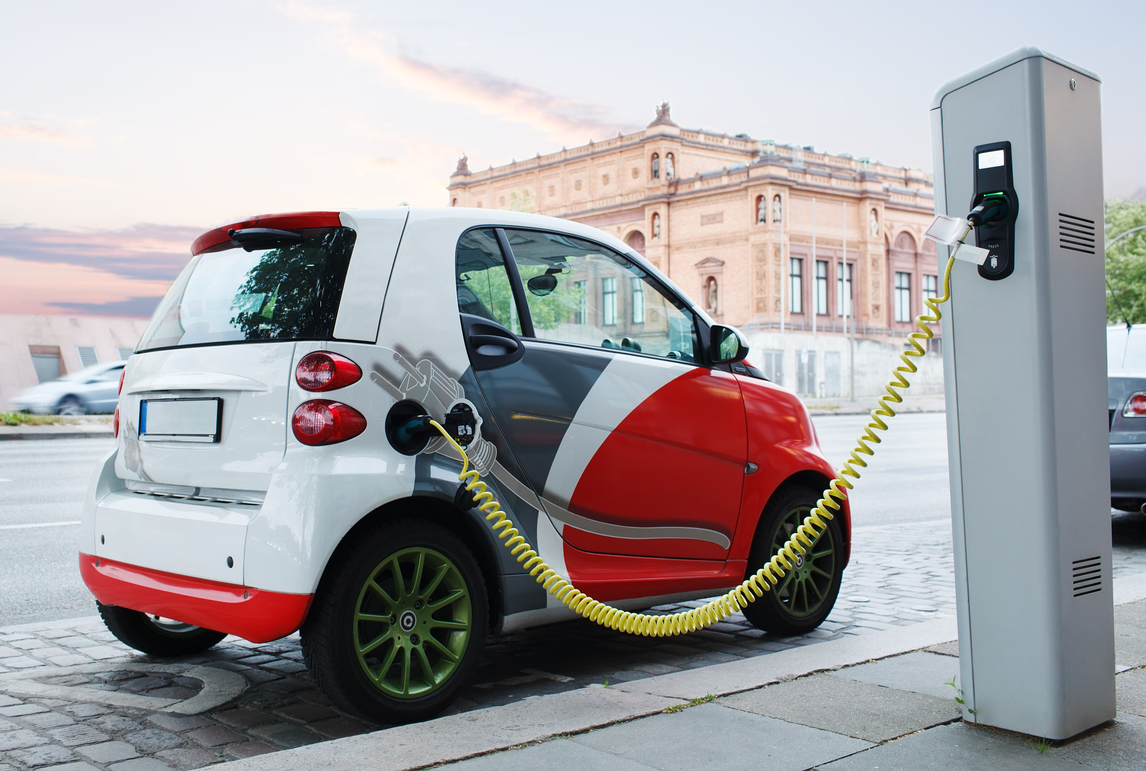 Elektroauto lädt an Straße – Ladevorgang an öffentlicher Wallbox im urbanen Raum.